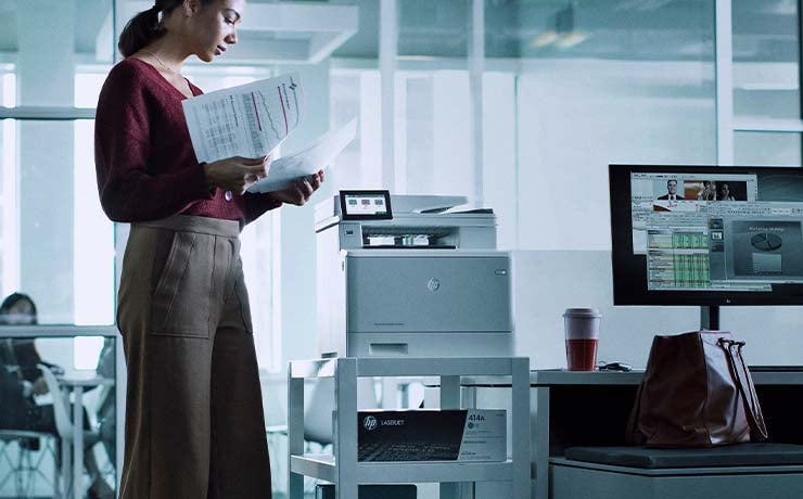 Kvinde står ved printer på kontor